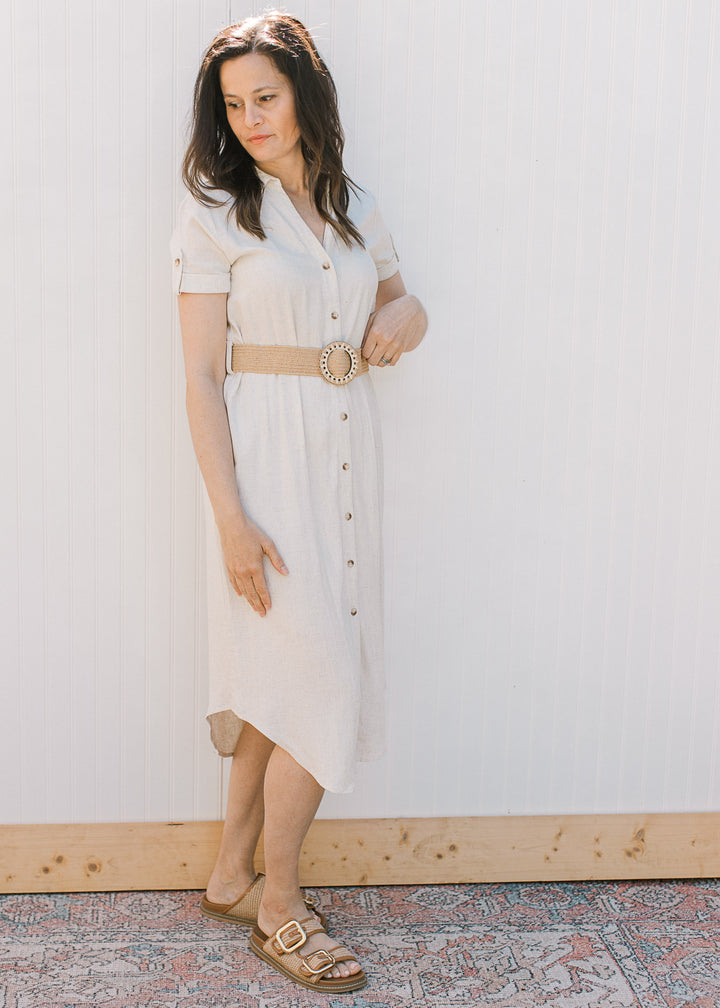 Side view of Model wearing a sandy linen dress with button front, collar, short sleeves and belt.