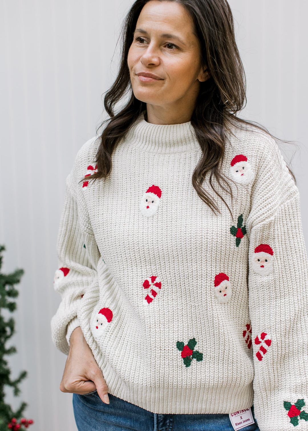 Front detail of cream Santa sweater showing textured knit, ribbed mock neck, Santa faces, candy canes and holly.