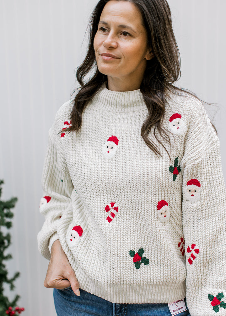 Front detail of cream Santa sweater showing textured knit, ribbed mock neck, Santa faces, candy canes and holly.