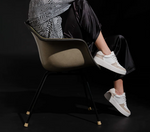 Model sitting wearing a white and taupe shoe with a platform sole and laces. 