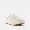 Front/outside view of cream sneakers with a paneled construction and a topstitch trim.