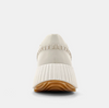 BAck view of cream sneakers made of faux leather with a paneled construction and a topstitch trim.