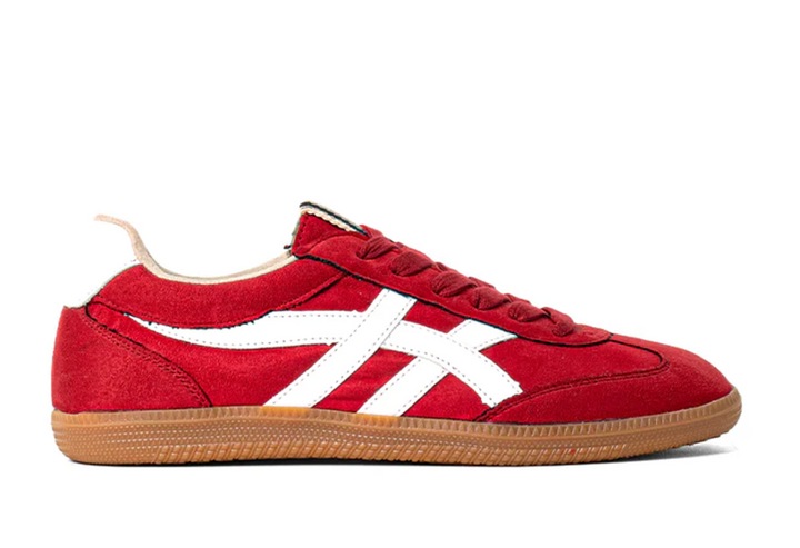 Side view of Deep red suede sneaker with white faux leather stripes, tan sole and red laces. 