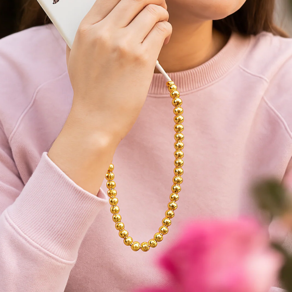 Model wearing a pink sweatshirt using a charger with gold beaded design.