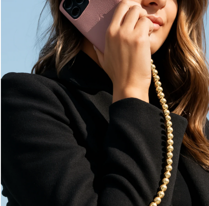 Model using a charger with gold beaded design wearing a black jacket. 