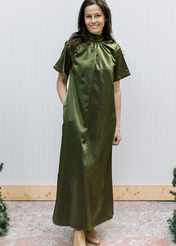 Front view of shimmery olive maxi dress with gathered mock neckline, short sleeves and hand in a side pocket.