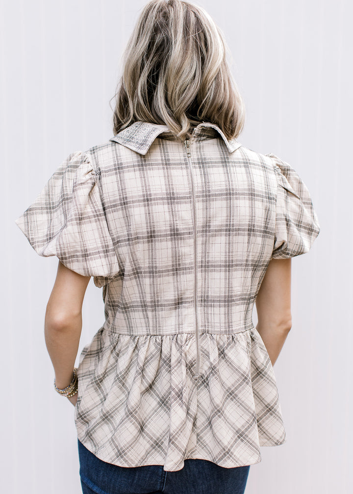  Back view of taupe and black plaid top showing exposed zipper, short bubble sleeves and gathered peplum hem.