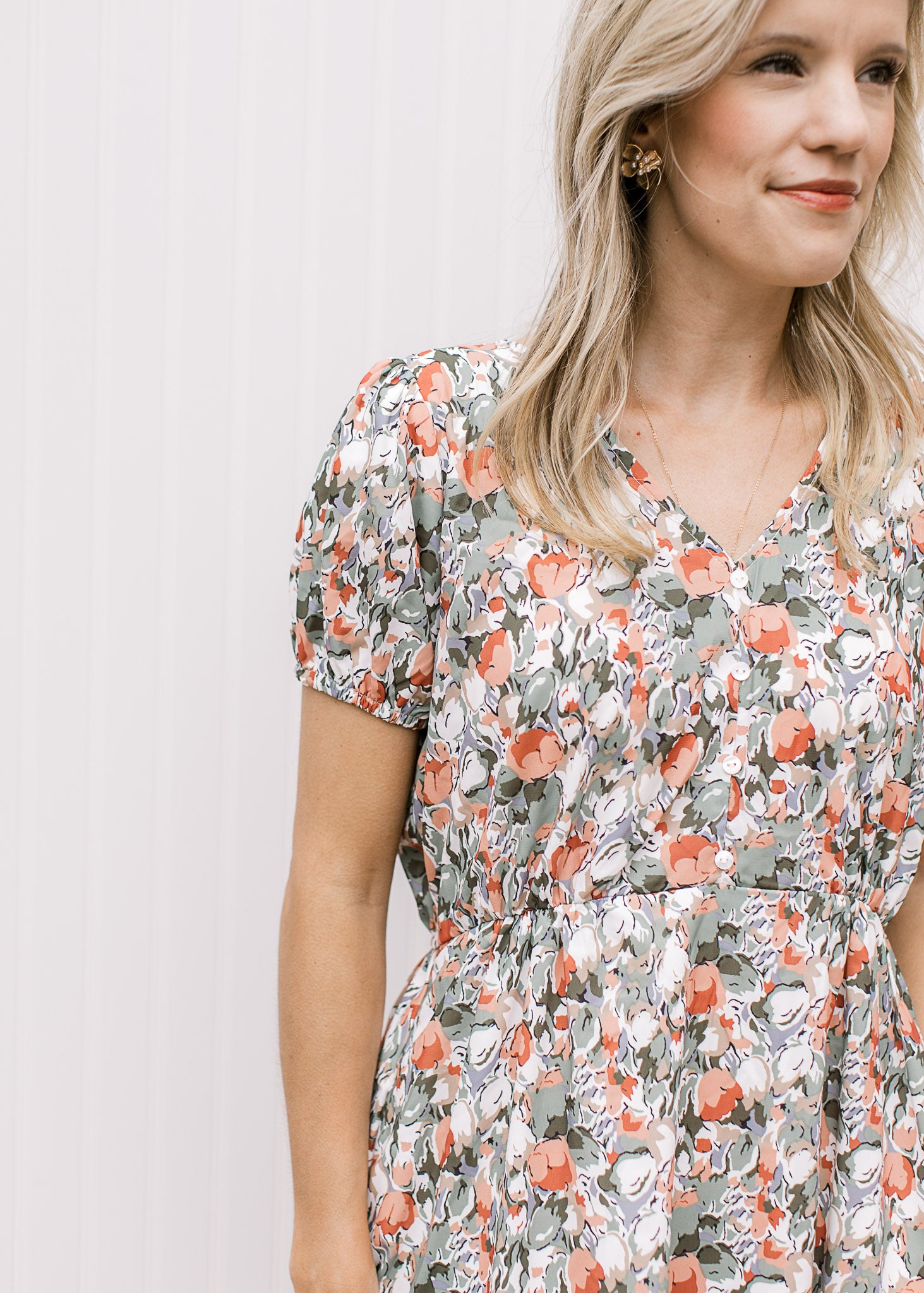 Close up of v-neck, short sleeves with elastic and elastic waist band on a white midi with tulips.