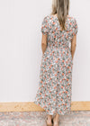 Back view of Model wearing a white midi with sage, peach and rust tulips and short sleeves. 