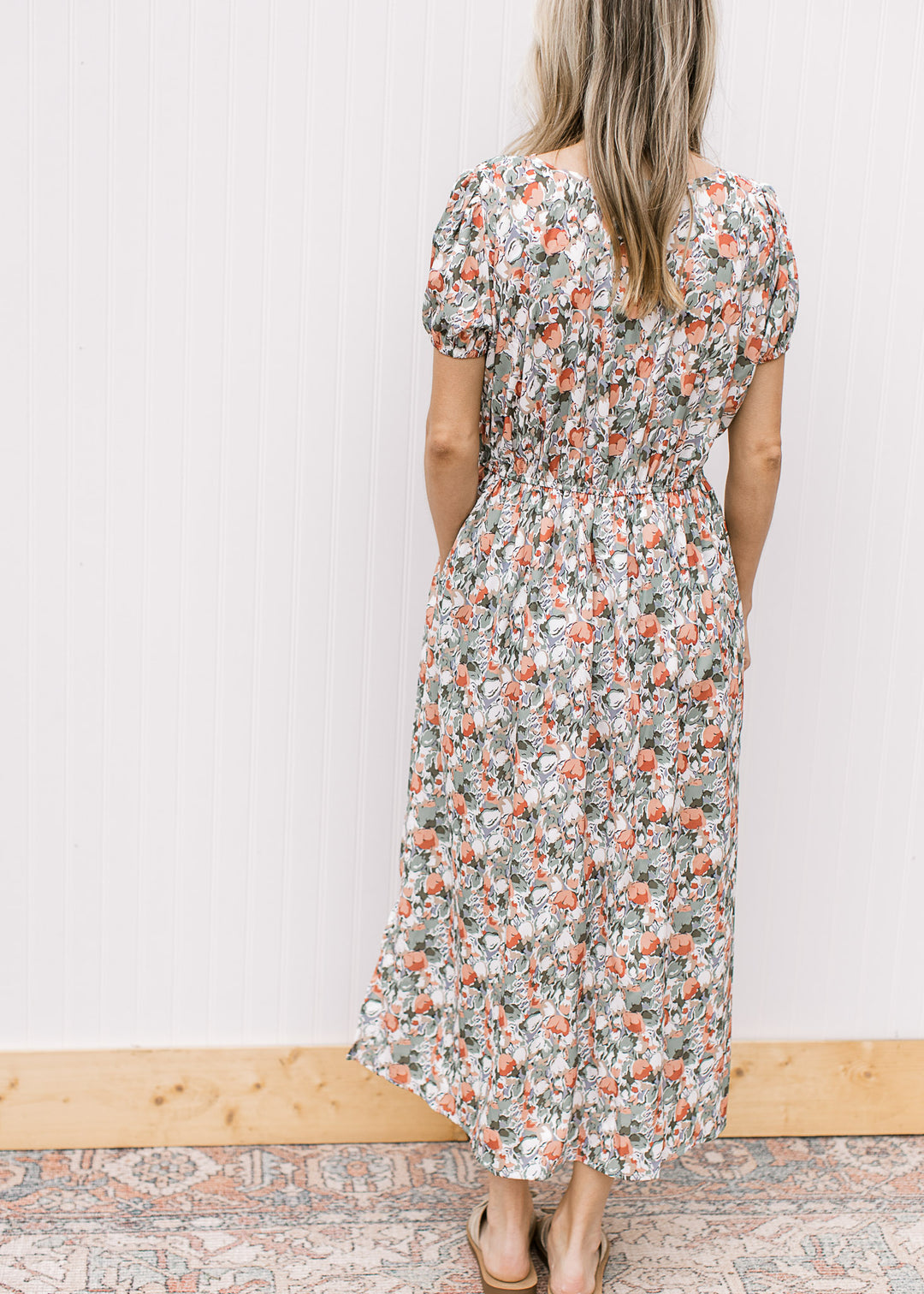 Back view of Model wearing a white midi with sage, peach and rust tulips and short sleeves. 