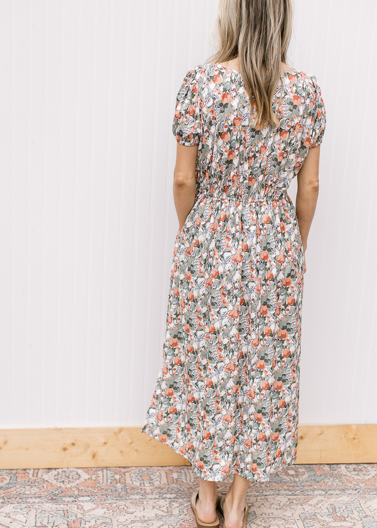 Back view of Model wearing a white midi with sage, peach and rust tulips and short sleeves. 