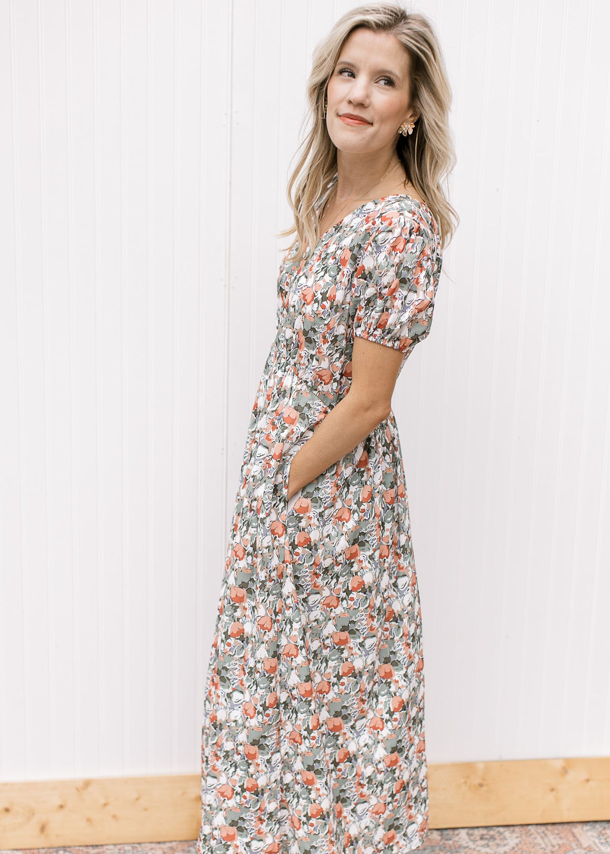 Model wearing a white midi with sage, peach and rust tulips, v-neck, pockets and short sleeves. 
