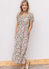 Model wearing sandals and a white midi with sage, peach and rust tulips, v-neck and short sleeves. 