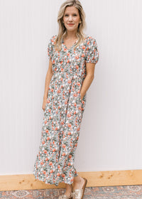 Model wearing sandals and a white midi with sage, peach and rust tulips, v-neck and short sleeves. 