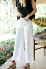 Model wearing wedges with white crop jeans with a raw hemline and tummy control.