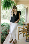 Model wearing a black top with white crop jeans with a raw hemline and tummy control.