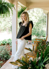 Model with her hand in the pocket of white crop jeans with a raw hemline and tummy control.