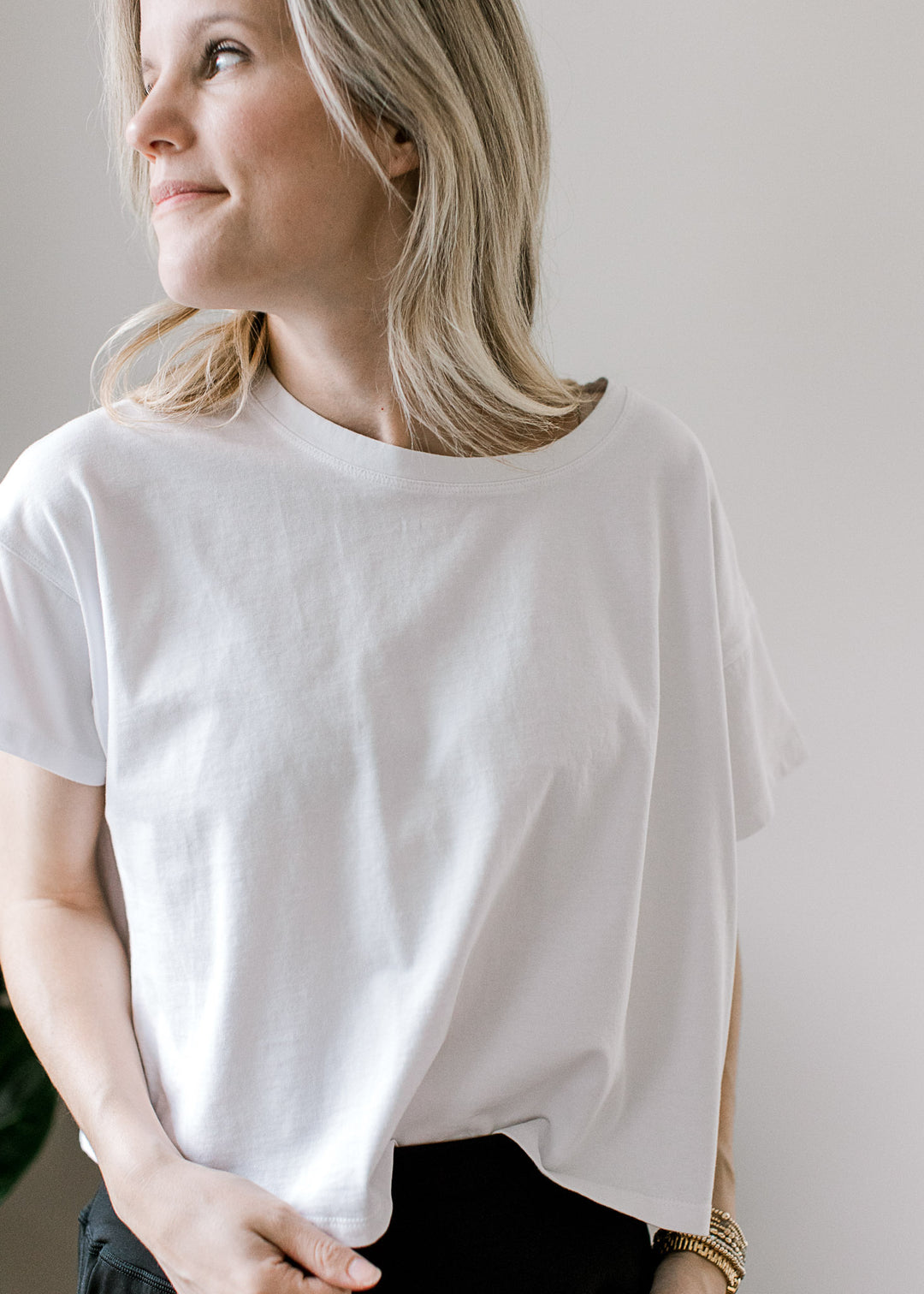 Model wearing a white lightweight top with short sleeves and a round neckline.