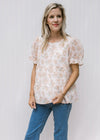 Model wearing jeans with a cream top with pink watercolor floral and sheer puff short sleeves