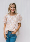 Model wearing a cream top with pink watercolor floral and sheer puff short sleeves 