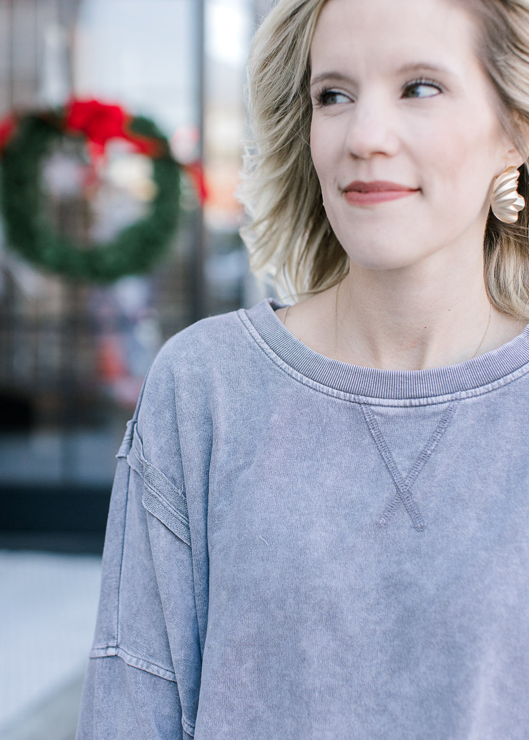 Close up of exposed hem and wide neck on a grayish blue sweatshirt with long sleeves. 