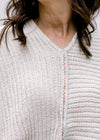 Close up of floral strip down the center of a cream cable knit sweater with kimono long sleeves. 