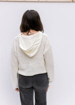 Back view of hoodie on a cream knit top with a slightly cropped hem and long sleeves. 