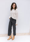 Model wearing jeans, booties and a cream knit hoodie with a slightly cropped hem and long sleeves. 
