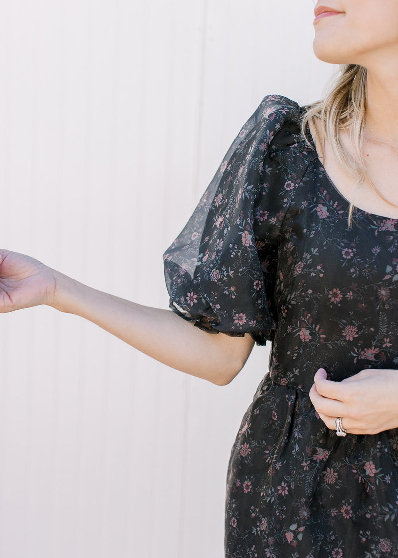 Close up of short bubble sleeves and pleated shoulders on a black dress with pink floral. 