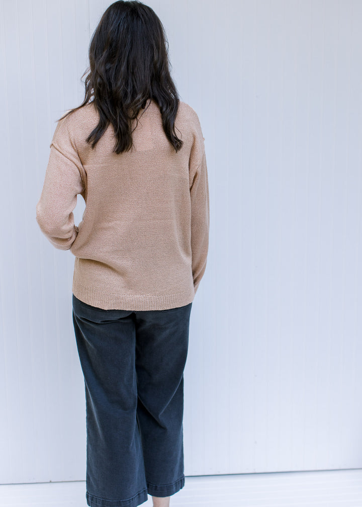 Back view of Model wearing an amber sweater with a patch pocket, exposed hem and long sleeves. 