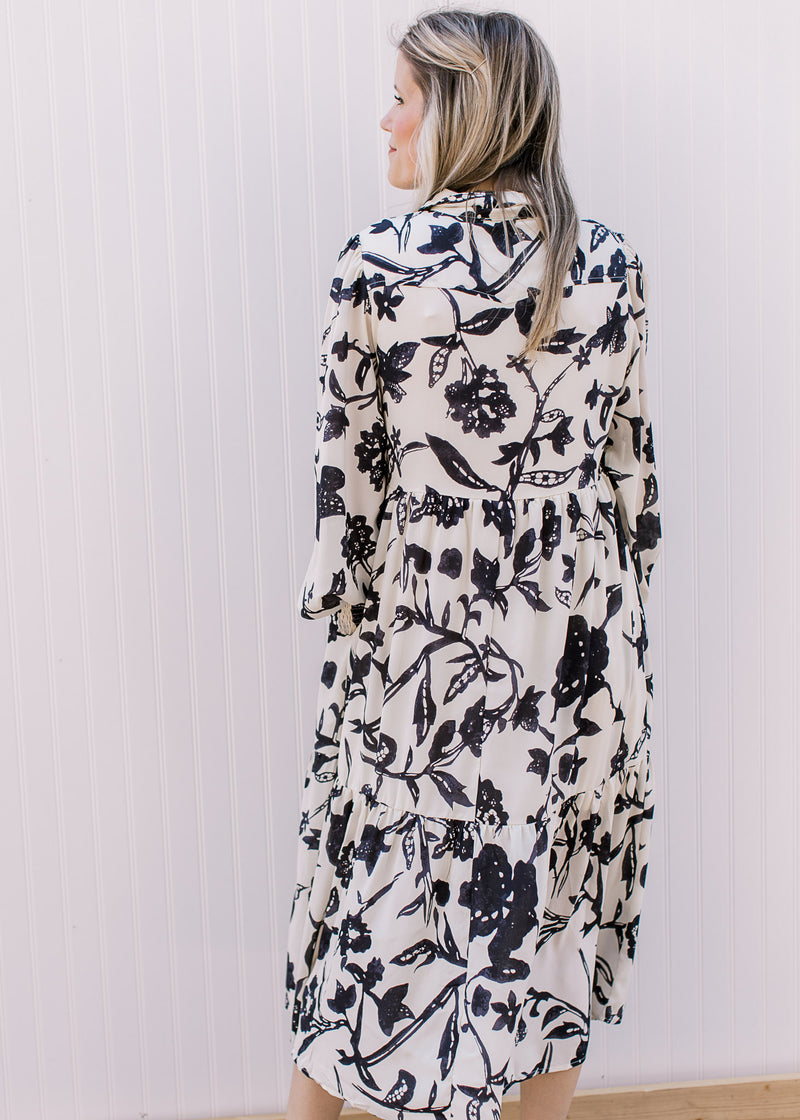 Back view of Model wearing a cream midi with navy flowers and long sleeves with elastic wrist.