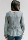 Back view of Model wearing a dotted dusty blue top with a keyhole closure and long sleeves.