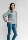 Model wearing jeans with Model wearing a dotted dusty blue top with a lace detail and long sleeves. 