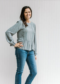 Model wearing jeans with Model wearing a dotted dusty blue top with a lace detail and long sleeves. 