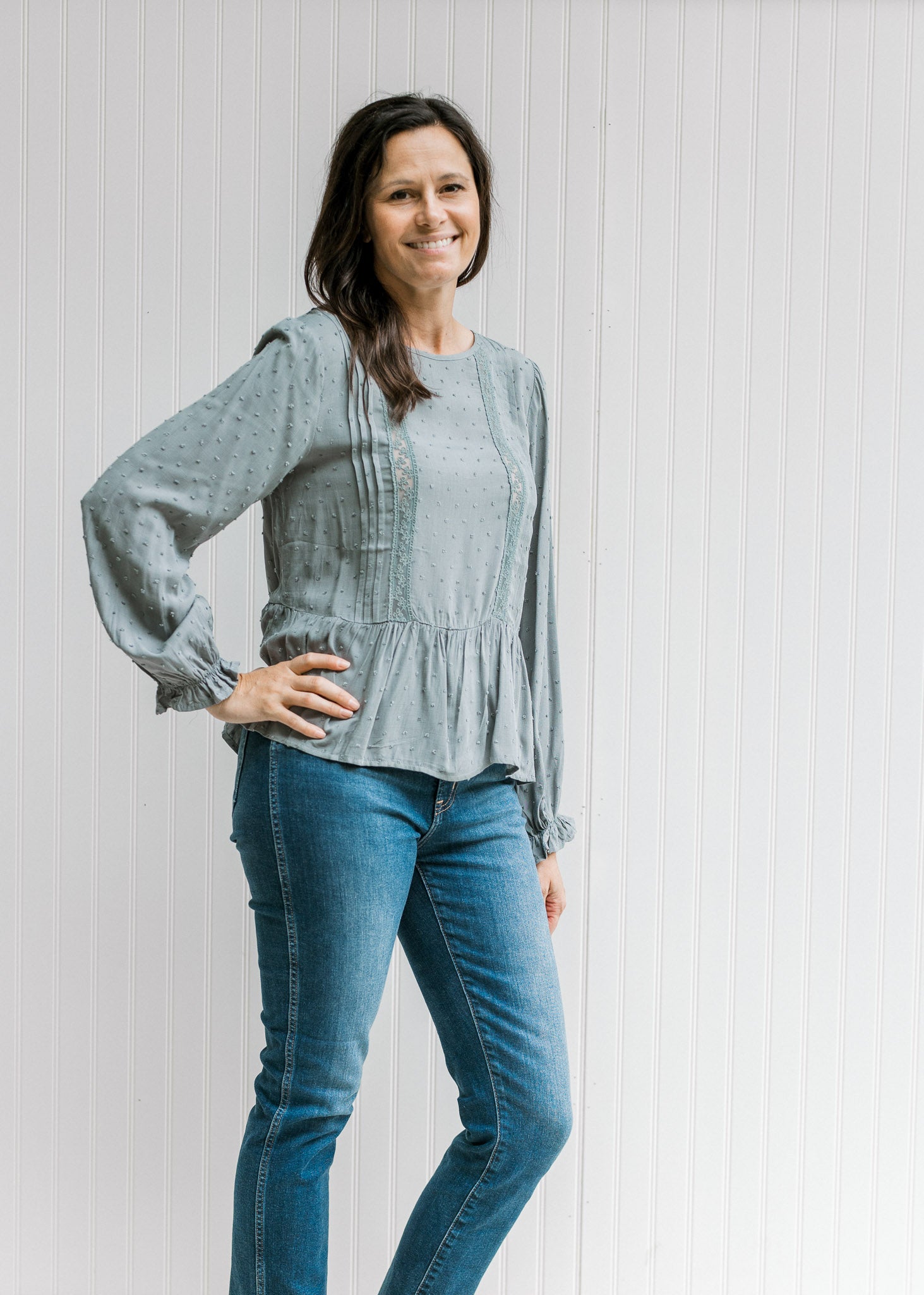 Model wearing jeans with Model wearing a dotted dusty blue top with a lace detail and long sleeves. 