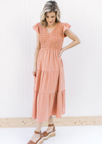 Model wearing an apricot midi with a smocked bodice, ruffle capped sleeves and a v-neck.