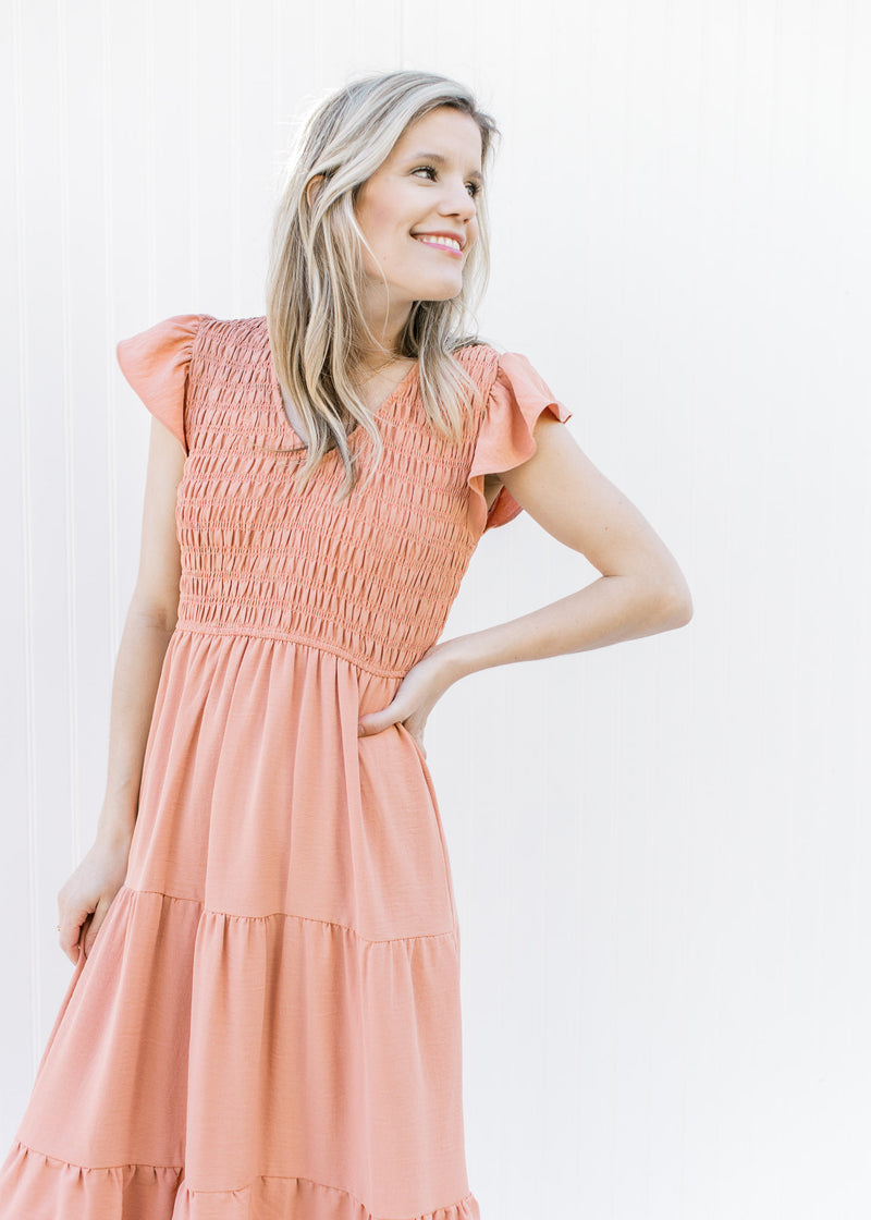 Close up of smocked bodice and ruffle cap sleeves on an apricot colored midi.