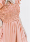 Close up of smocked bodice and v-neck on an apricot colored midi with flutter short sleeves.