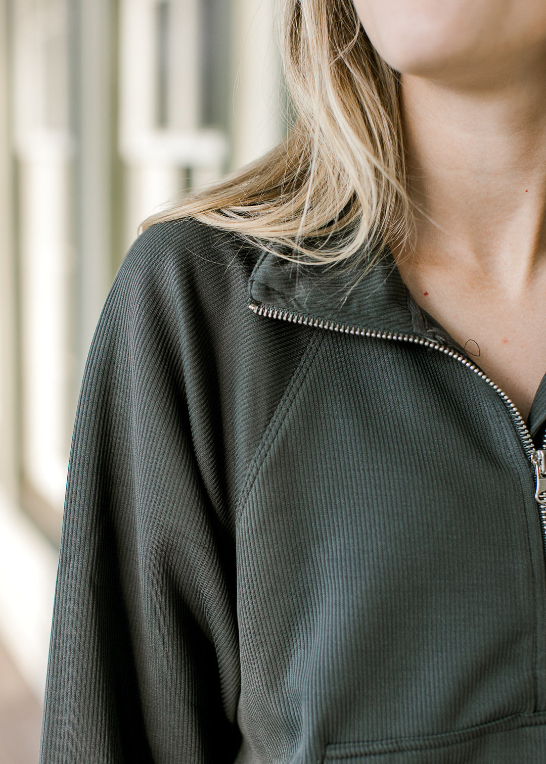 Close up of flap collar and quarter zip on a ribbed pullover with a front pouch pocket. 