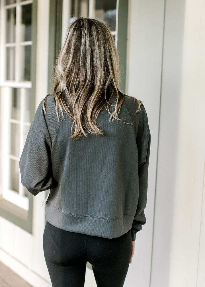 Back view of Model wearing an ash gray pullover with a quarter zip and front pouch pocket.