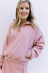 Model wearing a dusty pink pullover with zipper pockets and long sleeves with matching skort. 