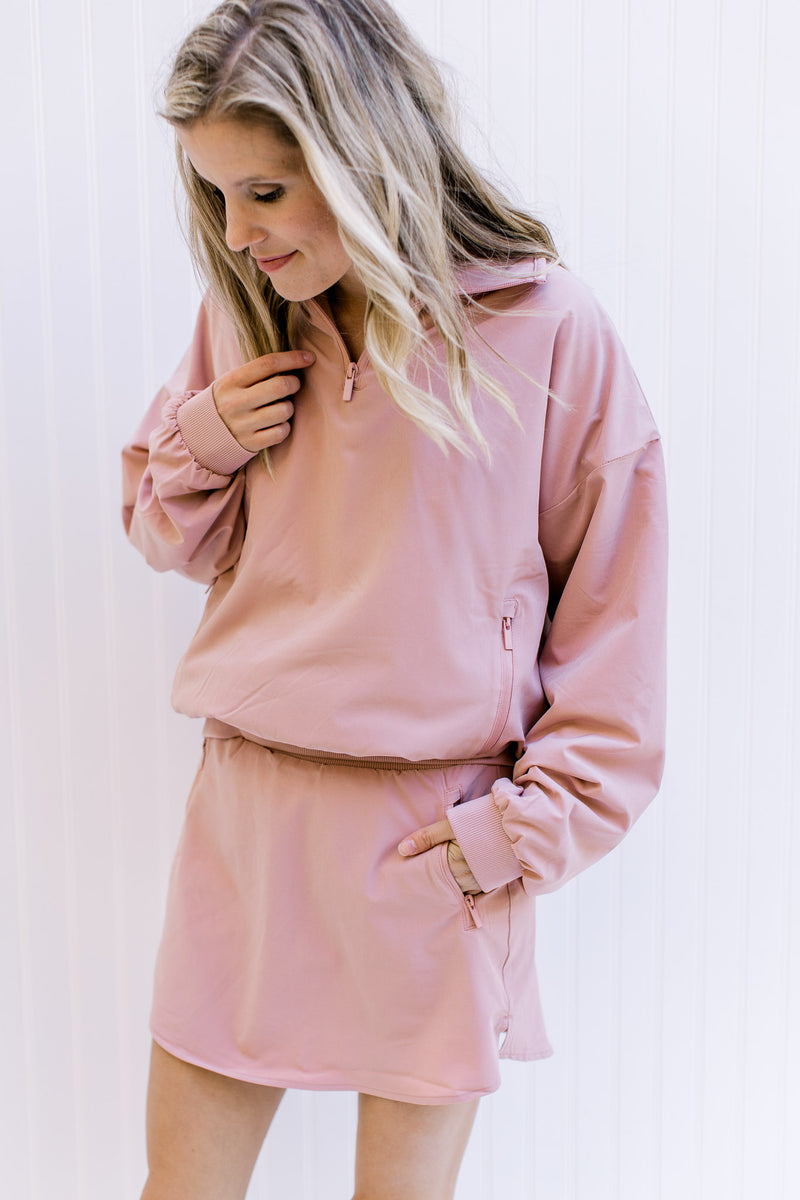 Model wearing a pink fleece lined skort with built in shorts, zipper pockets and elastic waist.