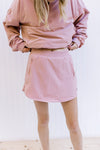 Model showing the elastic waist on a pink fleece lined skort with built in shorts and zipper pockets