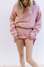 Model showing built in shorts on  a pink fleece lined skort with zipper pockets and elastic waist.