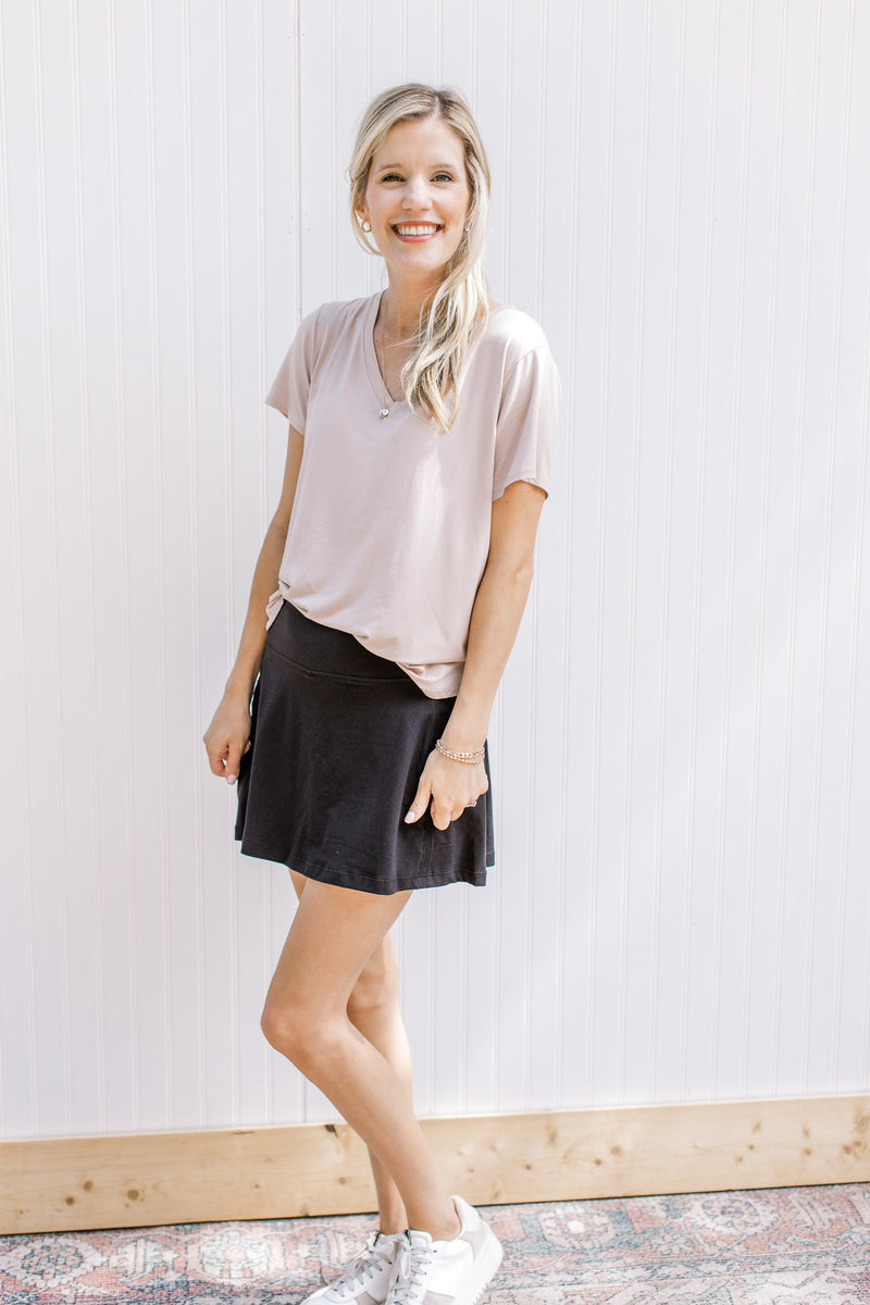 Model wearing a black pleated skort with elastic waistband and built in shorts.