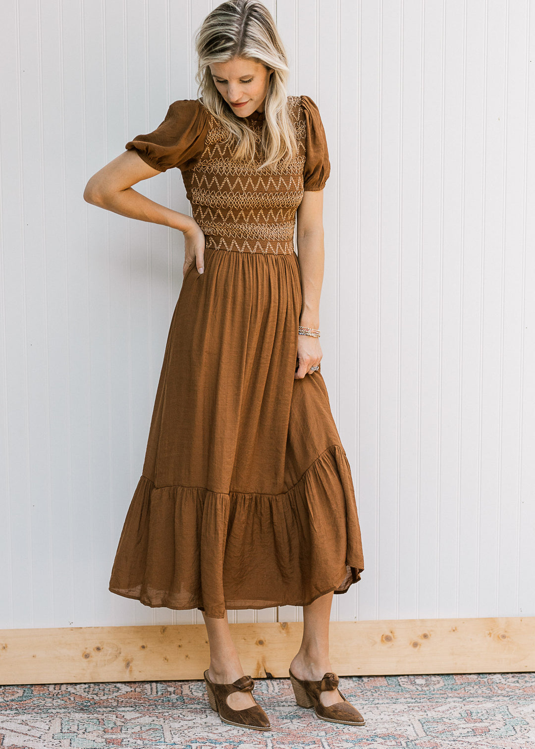 Model wearing a brown short sleeve midi with a taupe embroidered smocked bodice and flowy skirt. 