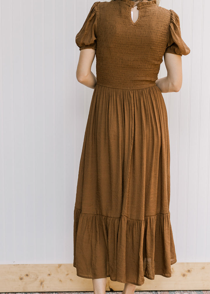 Back view of brown midi with a smocked bodice, short sleeves, keyhole and flowy skirt. 
