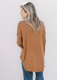 Back view of Model wearing a camel flowy sweater with long sleeves, cowl neck and split sides. 