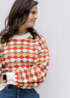 Model wearing a cream, brown, camel and rust wave sweater with bubble long sleeves and a round neck.