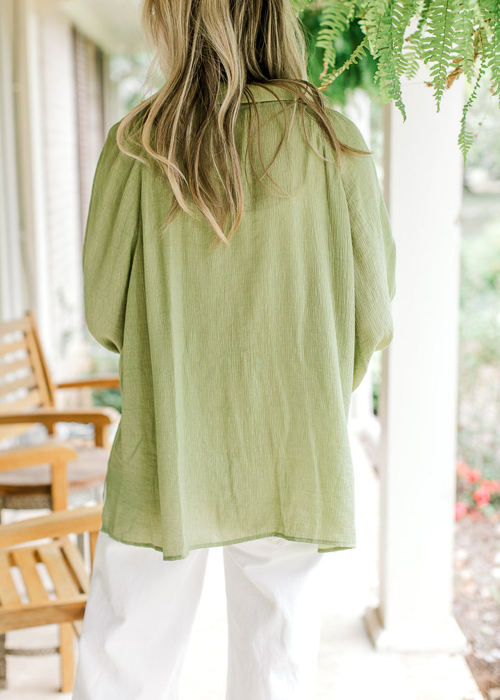 Back view of Model wearing an avocado green top with a collar and long sleeve.